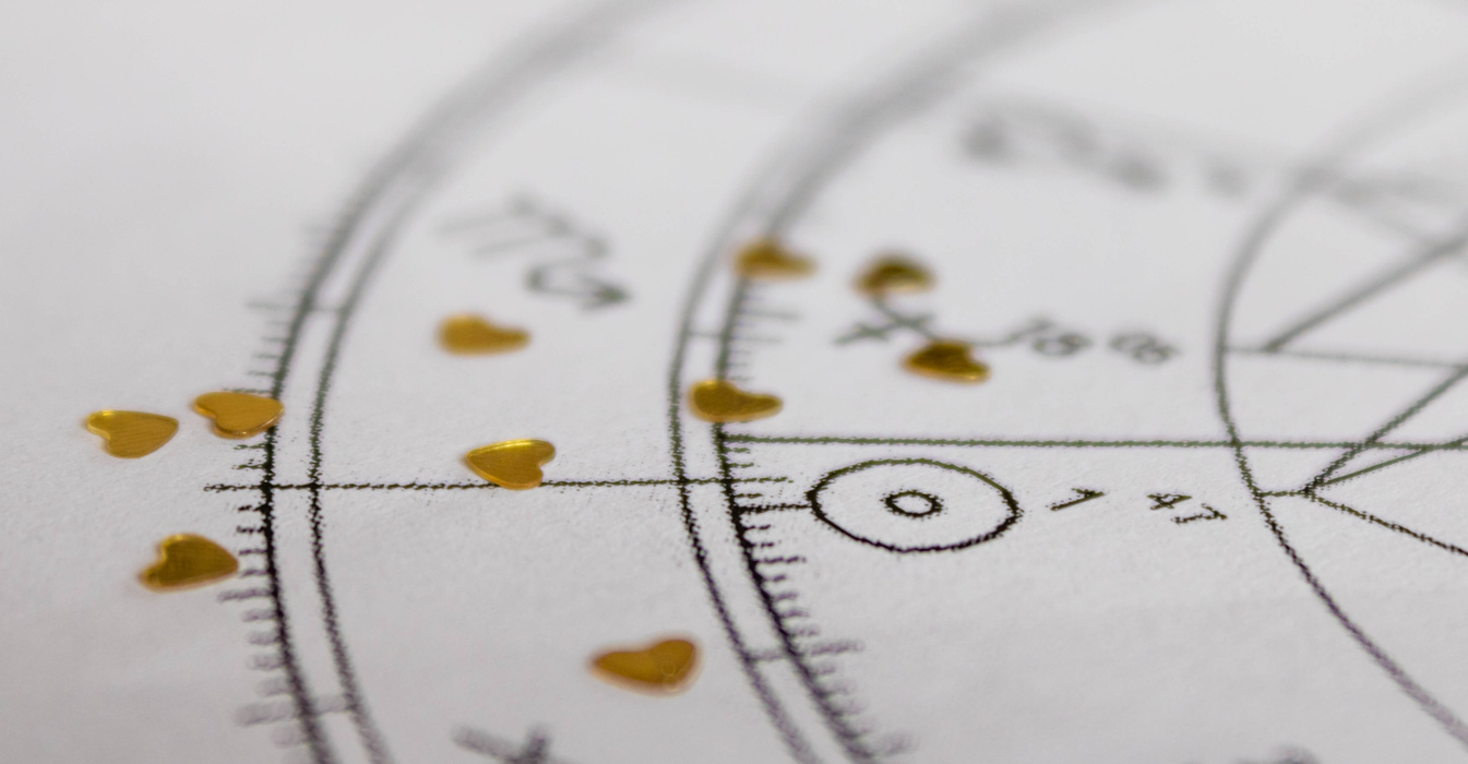 Detail of printed astrology chart with astrology Sun and golden heart shaped sequins